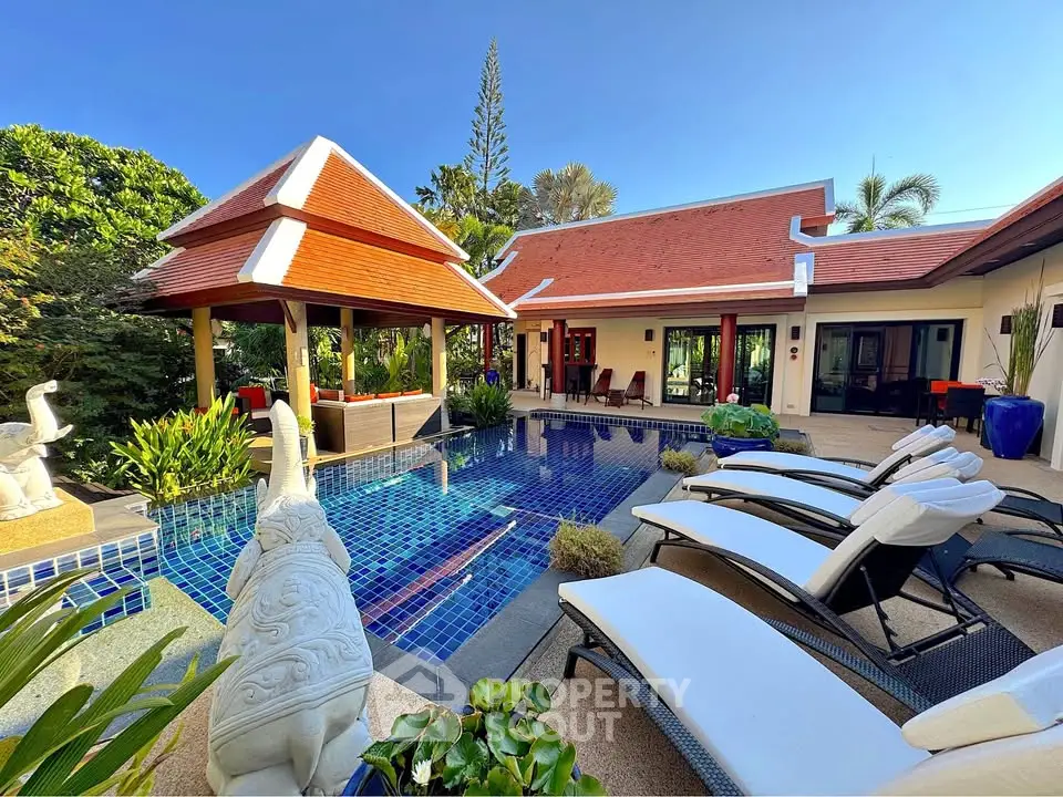 Luxurious villa with private pool and sun loungers, surrounded by lush greenery and elegant architecture.
