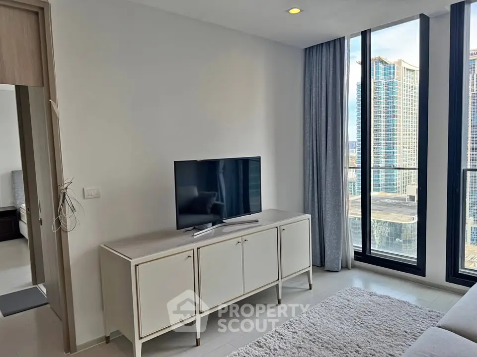 Modern living room with sleek TV stand and floor-to-ceiling windows offering stunning city views.