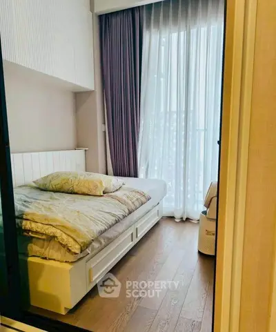 Cozy bedroom with large window and elegant curtains, featuring a comfortable bed and wooden flooring.
