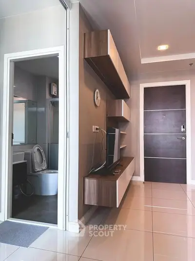 Modern apartment interior with sleek TV unit and adjacent bathroom, showcasing contemporary design and functionality.