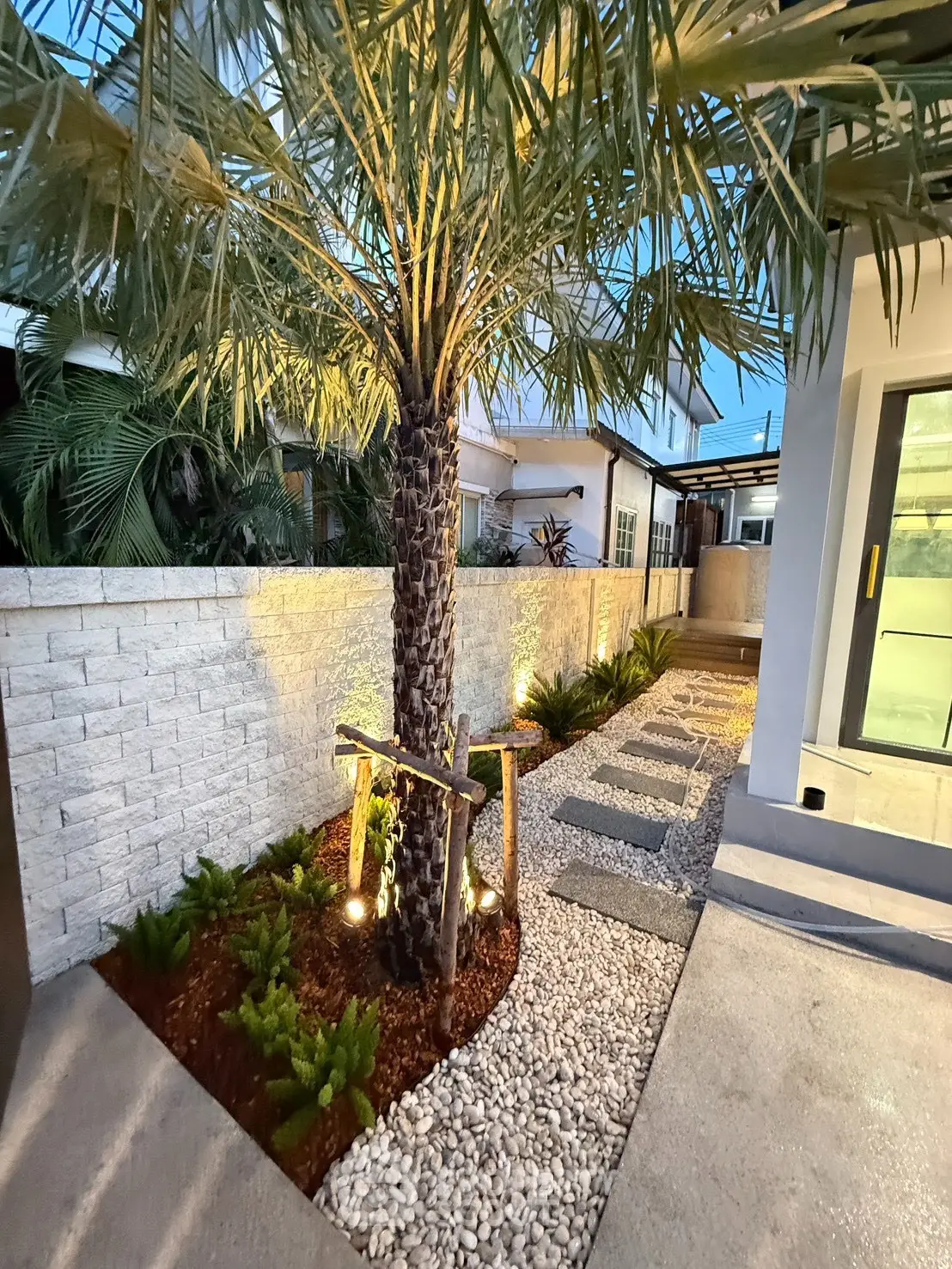 Stunning modern garden with palm tree and elegant pathway lighting, perfect for serene outdoor living.
