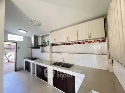 Spacious kitchen with modern cabinetry and dual sink, featuring open layout and gas stove.