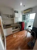 Modern compact kitchen with open layout and balcony access, featuring sleek appliances and wooden flooring.