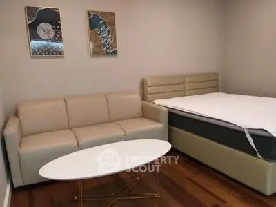 Modern bedroom with stylish decor, featuring a cozy sofa and elegant bed on wooden flooring.