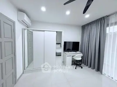 Modern bedroom with sleek design, featuring a mirrored wardrobe, desk, and large window with curtains.