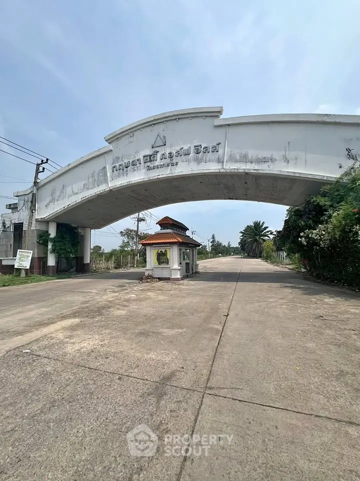 Grand entrance to a residential community with a security booth and lush greenery.