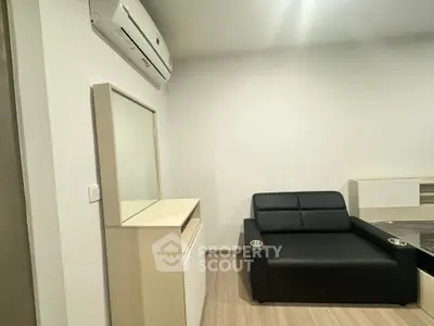 Modern living room with sleek black sofa and air conditioning unit, perfect for comfort and style.