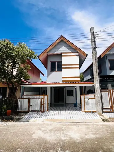 Charming two-story house with unique roof design and spacious driveway in a serene neighborhood.