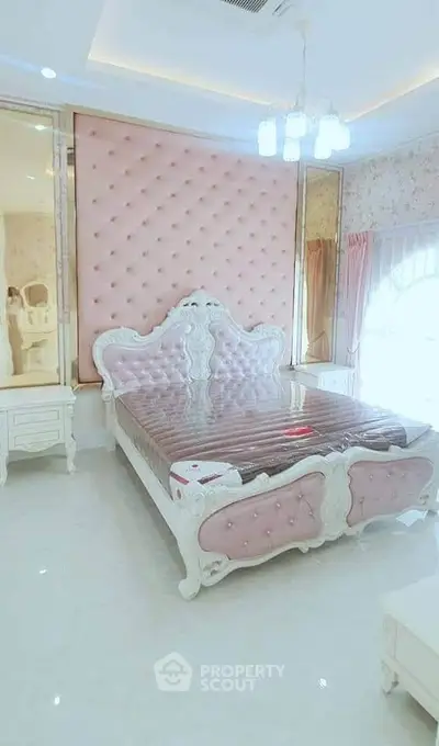 Luxurious bedroom with elegant pink tufted headboard and ornate white furniture.