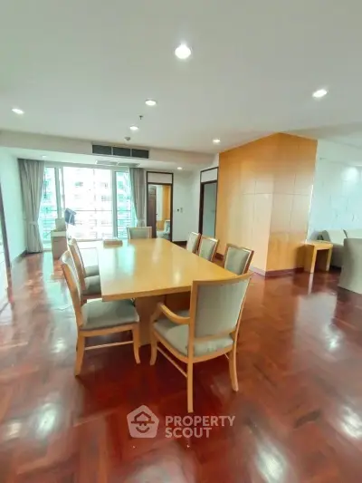 Spacious dining area with elegant wooden flooring and modern furniture in a bright apartment.