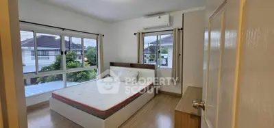 Bright bedroom with large windows and modern furnishings in a cozy home.