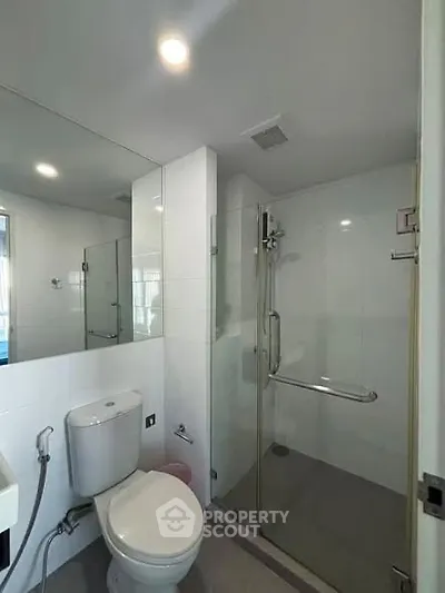 Modern bathroom with glass shower enclosure and sleek fixtures.
