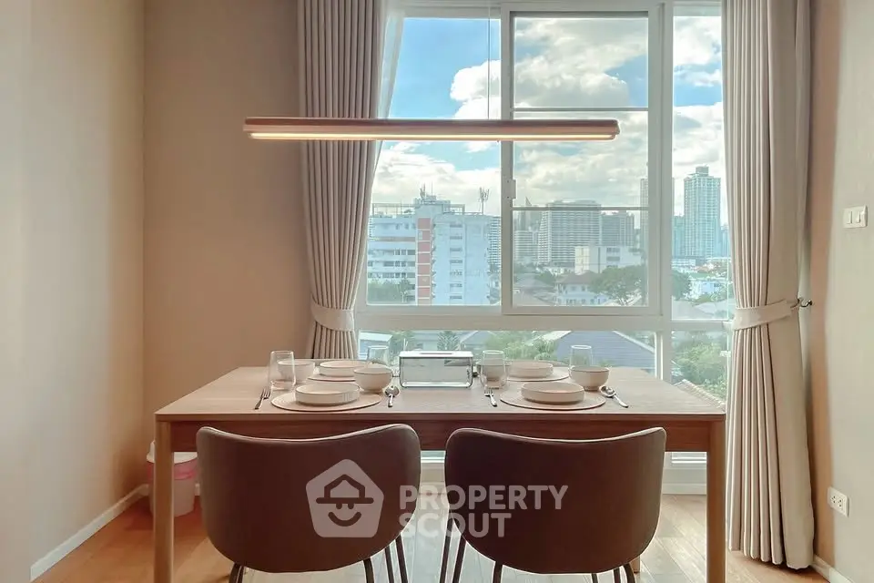 Modern dining area with city view, featuring elegant table setting and large window.