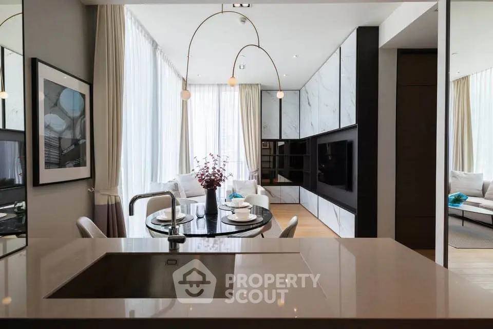 Luxurious modern living room with open kitchen and elegant dining area, featuring sleek design and ample natural light.