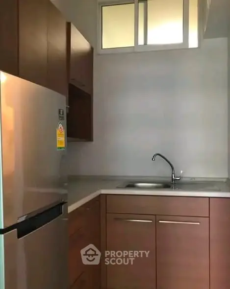 Modern compact kitchen with sleek cabinetry and stainless steel fridge