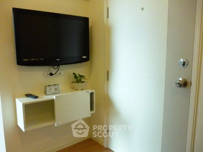 Modern apartment entrance with wall-mounted TV and sleek storage unit.