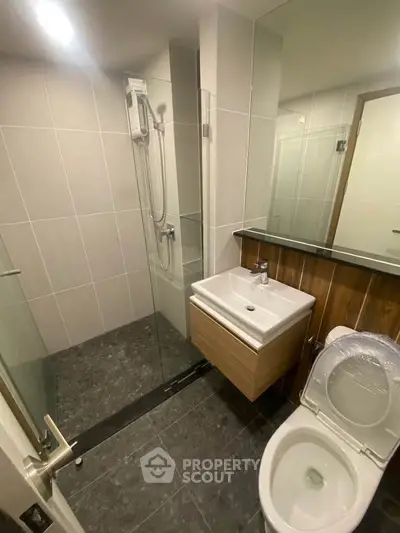 Modern bathroom with sleek fixtures and glass shower enclosure in a contemporary apartment.