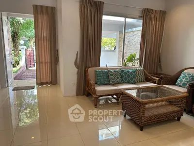 Charming living room with wicker furniture and garden view, perfect for relaxation.