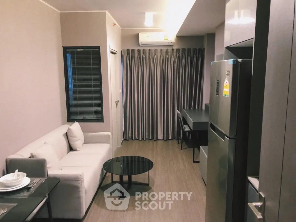 Modern living room with sleek furniture and open kitchen layout in a stylish apartment.
