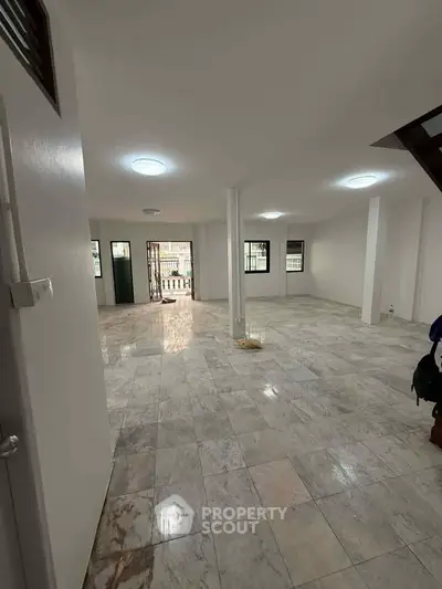 Spacious open-plan living area with marble flooring and ample natural light.