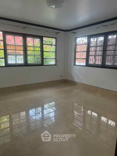 Spacious empty room with large windows and tiled flooring, perfect for customization.