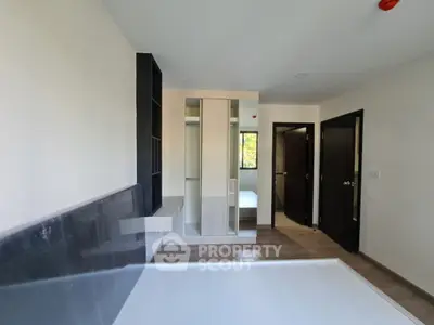 Modern bedroom with sleek design and ample natural light, featuring built-in wardrobe and minimalist decor.