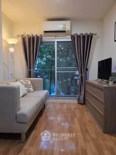 Cozy living room with modern decor, featuring a comfy sofa, sleek TV stand, and a view of lush greenery through large windows.