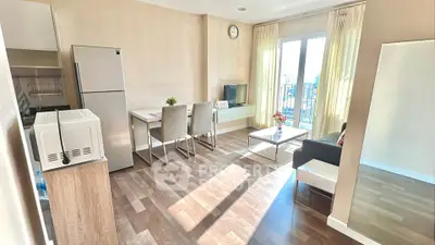 Bright modern living room with dining area and city view, featuring sleek furniture and natural light.