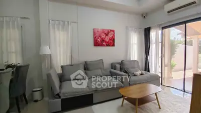 Charming living room with cozy gray sofas, modern decor, and natural light from large windows.