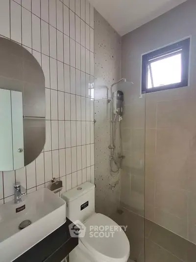 Modern bathroom with sleek fixtures and natural light from a small window.