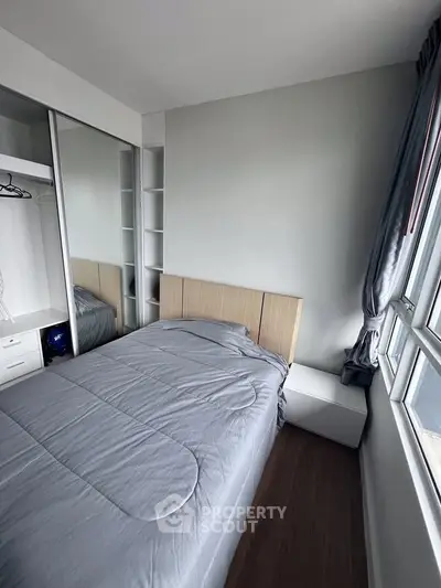 Cozy bedroom with modern design, featuring a comfortable bed and ample natural light from large windows.
