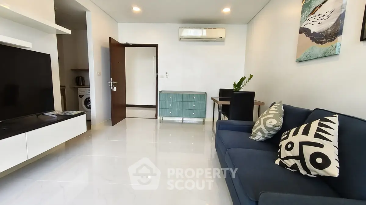 Modern living room with sleek design, featuring a blue sofa, wall art, and a flat-screen TV for stylish comfort.