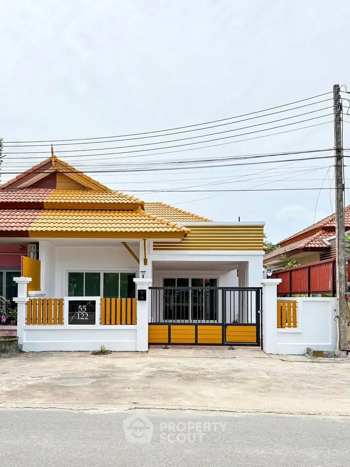 Charming single-story house with vibrant yellow accents and gated entrance.