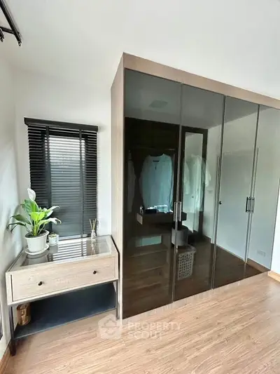Modern bedroom with sleek glass wardrobe and stylish wooden flooring