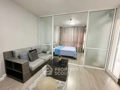 Modern studio apartment with sliding glass doors separating living and bedroom areas, featuring sleek furniture.