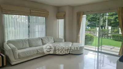 Spacious living room with white leather sectional and garden view