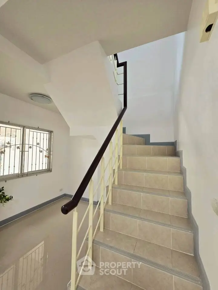 Bright stairway with modern railing and tiled steps in a residential building.