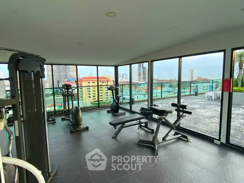 Spacious gym with panoramic city views and modern fitness equipment.