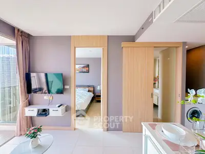 Modern apartment interior with open living space and bedroom view, featuring sleek design and natural light.