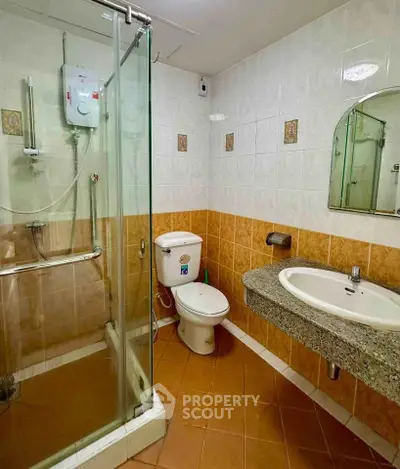Modern bathroom with glass shower, toilet, and granite sink in stylish tile setting.
