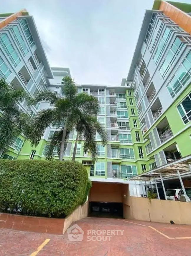 Modern apartment building with vibrant green facade and lush palm trees