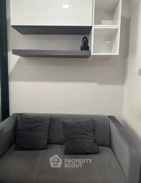 Cozy modern living room with sleek gray sofa and minimalist shelving.