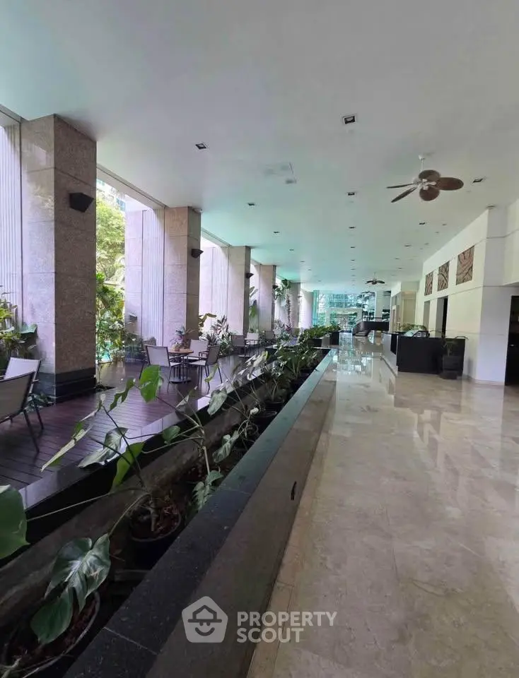 Spacious building entrance with elegant marble flooring and lush indoor plants