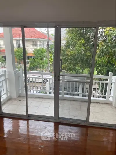 Charming balcony view with sliding glass doors and polished wooden floors, perfect for relaxation.