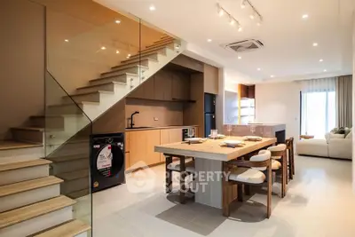 Modern open-plan kitchen and dining area with stylish staircase and cozy living room.