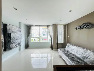 Spacious living room with large window, modern decor, and natural light.