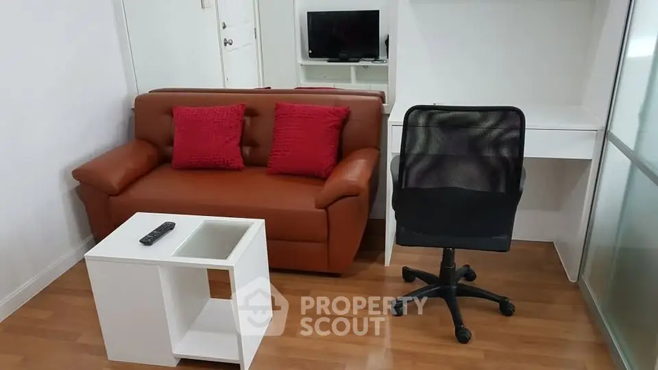 Cozy living room with brown sofa, red cushions, and modern office chair on wooden floor.