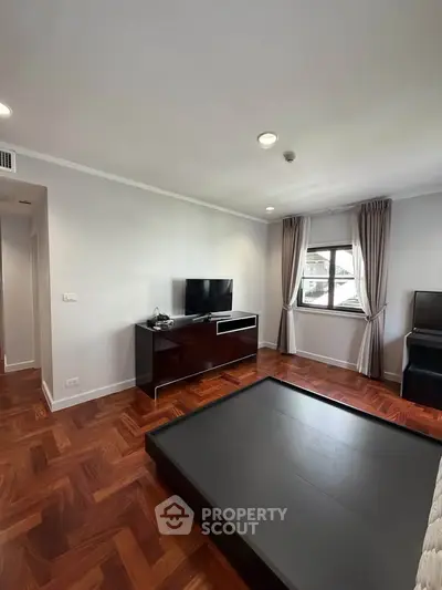 Spacious bedroom with modern decor and large window offering natural light.