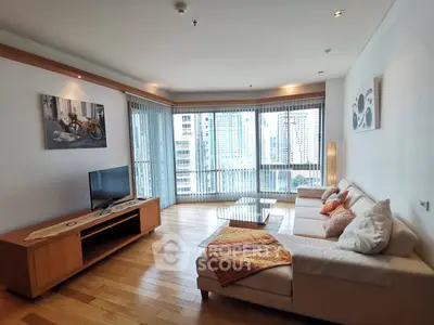 Spacious living room with modern decor and city view, featuring a cozy sofa and entertainment center.