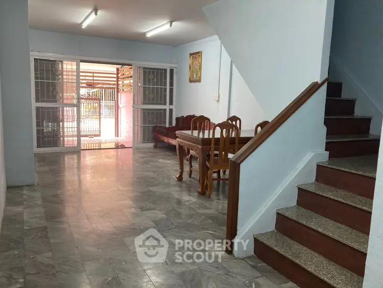 Spacious living area with marble flooring and wooden staircase